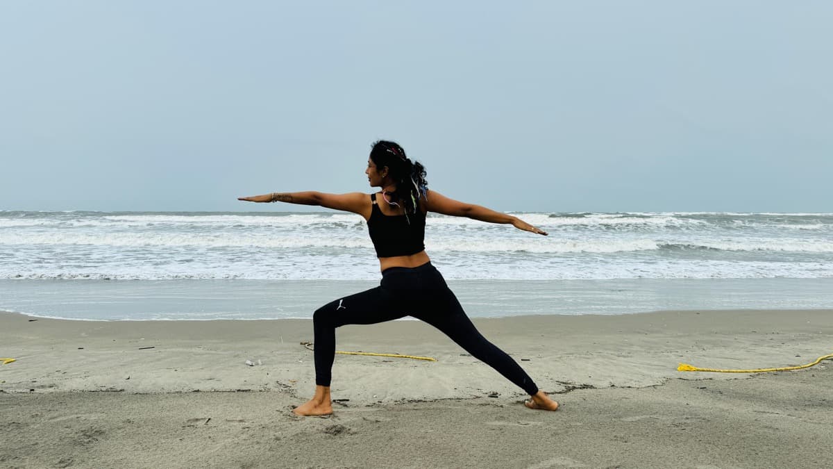 Warrior II arms-wide pose by the ocean
